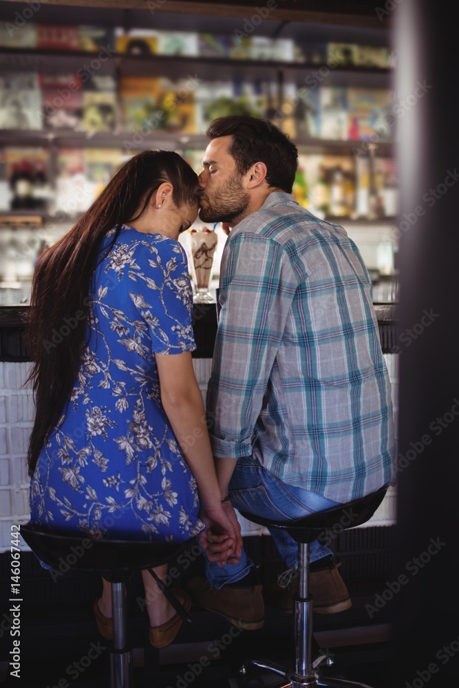 Affectionate man holding hands while kissing woman at counter Affectionate man holding hands while kissing woman at counter