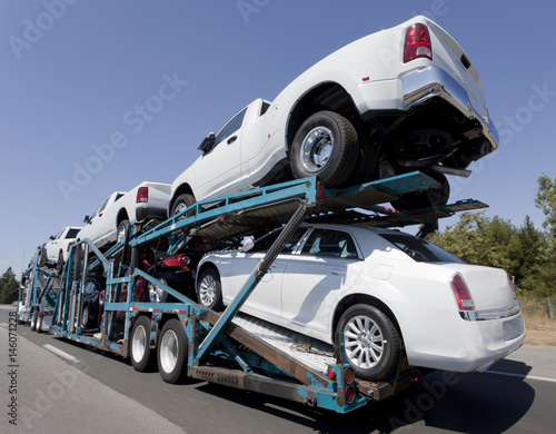 Rear view of trailer of new cars and trucks speeding to market.