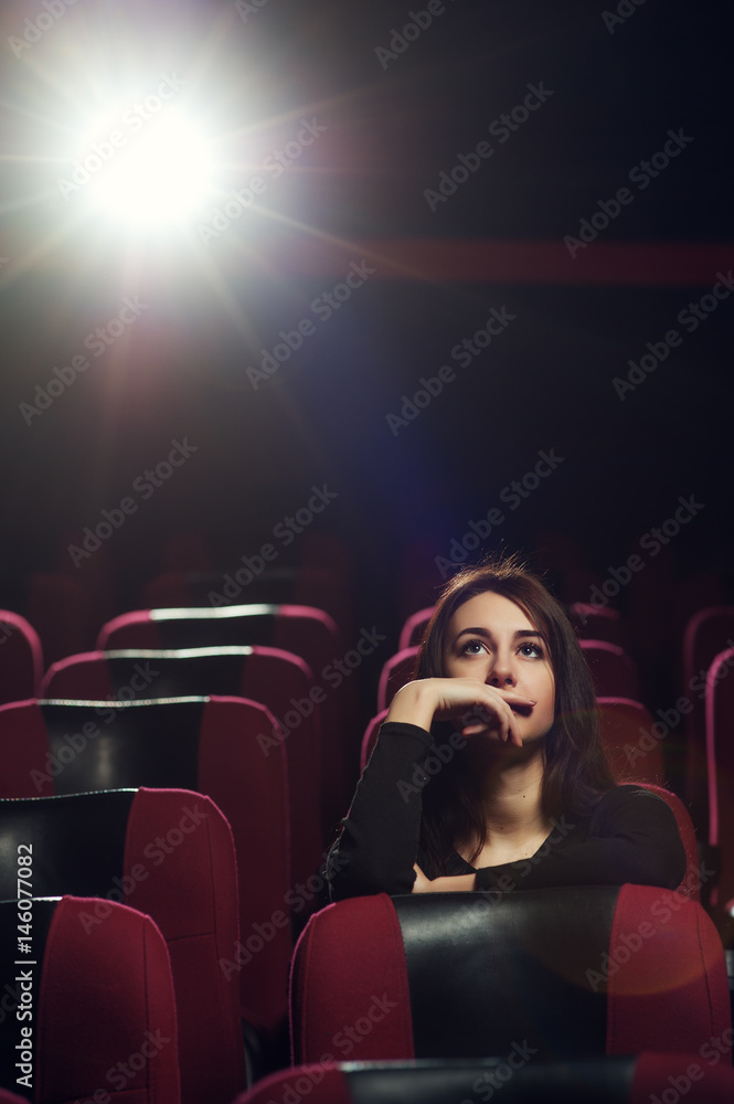 Beautiful brunette girl sitting in cinema theater