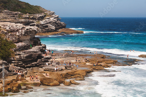 Photography Crowds of tourists relaxing and sunbathing by a  cliff in Tamarama beach in a sunny afternoon of summer