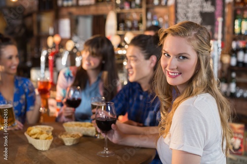 Portrait of smiling woman holding drink with friends