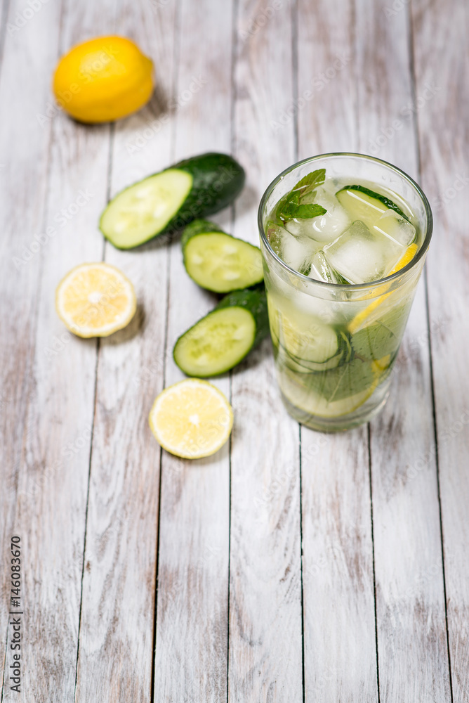 Fototapeta premium Water with lemon, mint and cucumber on wooden light background. Water Detox.