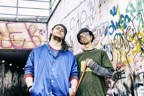 two rap singers with a dog in a subway with graffiti in the background