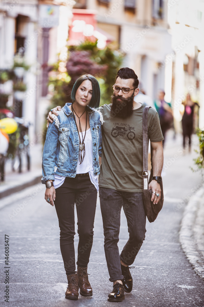 Couple de jeune hipster marchant bras dessus, bras dessous, dans la rue