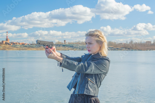 girl aiming a pistol at the background of the lake.