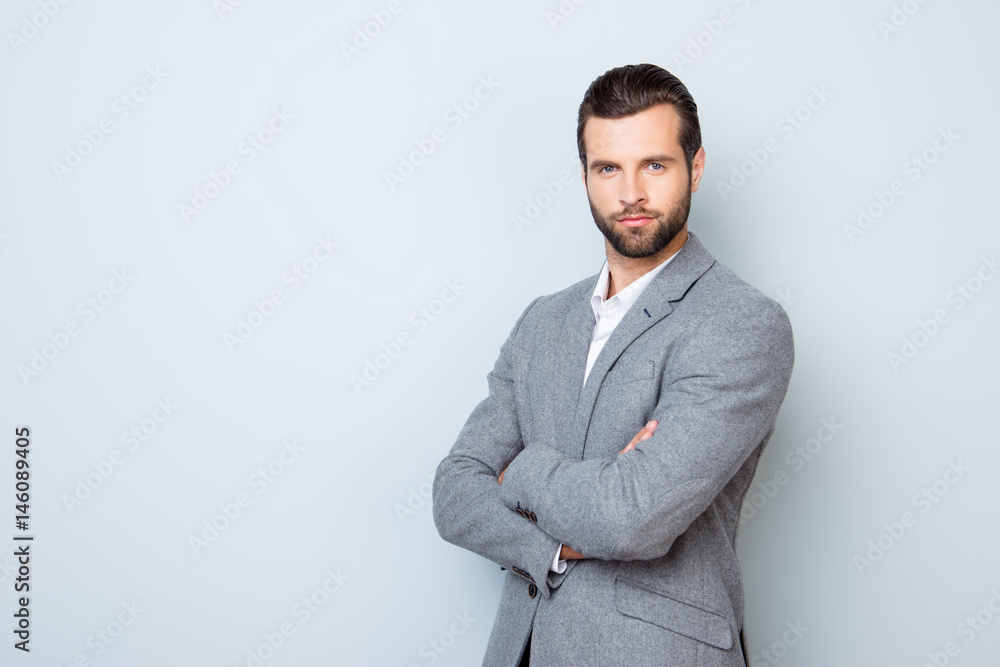 Portrait of handsome successful respected businessman in formal clothing standing with crossed hands against gray background Portrait of handsome successful respected businessman in formal clothing standing with crossed hands against gray background