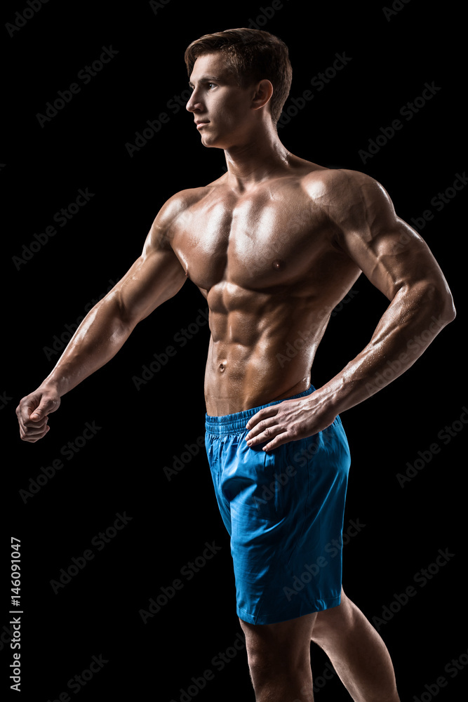 Muscular and fit young bodybuilder fitness male model posing over black background. Muscular and fit young bodybuilder fitness male model posing over black background.