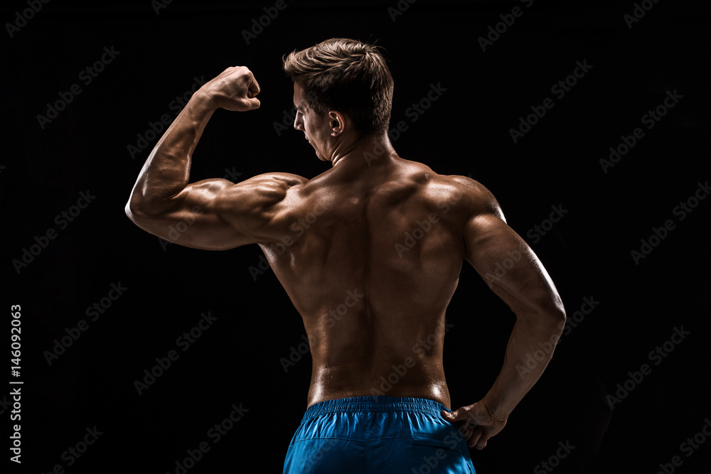Strong Athletic Man Fitness Model posing back muscles, triceps over black background Strong Athletic Man Fitness Model posing back muscles, triceps over black background