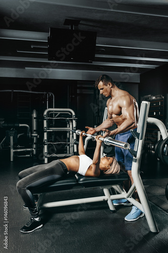 Fitness instructor exercising with his client at the gym.