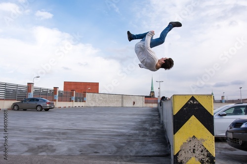 Young boy jumping somersault on the street.