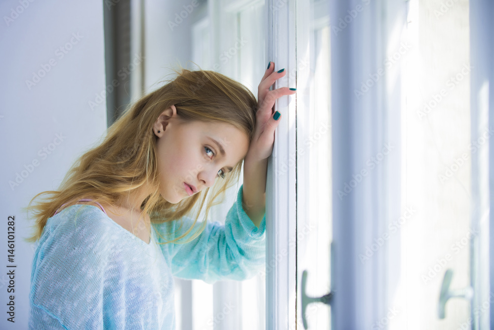 Pretty girl with blue eyes standing at window