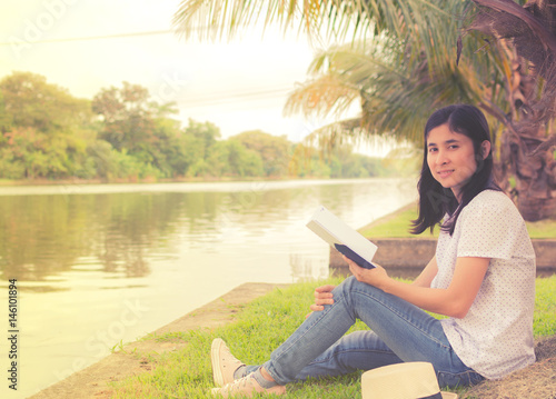 young beautiful woman relaxing in park nearby lake © chanyutcb