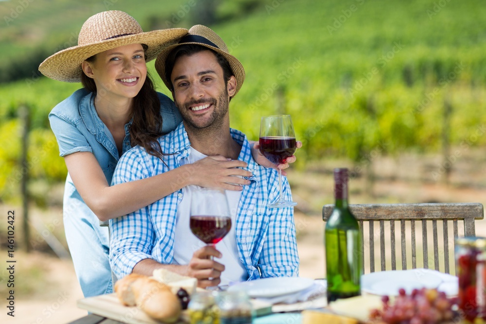 Portrait of young couple holding red wine at table