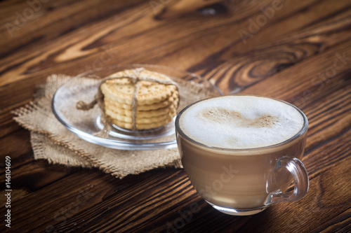 A cup of coffee and small cookies on an antique wooden table photo