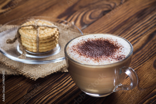 A cup of coffee and small cookies on an antique wooden table photo