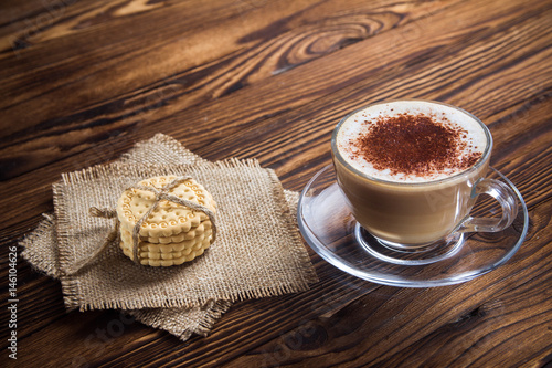 A cup of coffee and small cookies on an antique wooden table photo