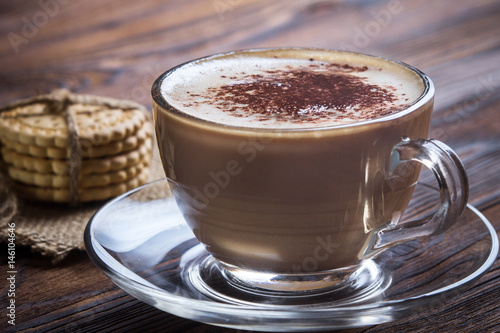 A cup of coffee and small cookies on an antique wooden table