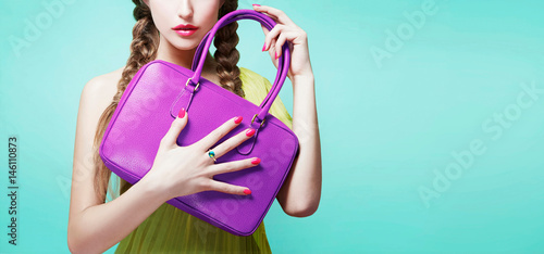 Obraz na płótnie Young girl holding her purple color handbag purse isolated on aqua blue background with copy space