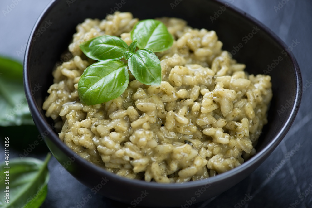Close-up of risotto with spinach in a black bowl, selective focus, studio shot Close-up of risotto with spinach in a black bowl, selective focus, studio shot