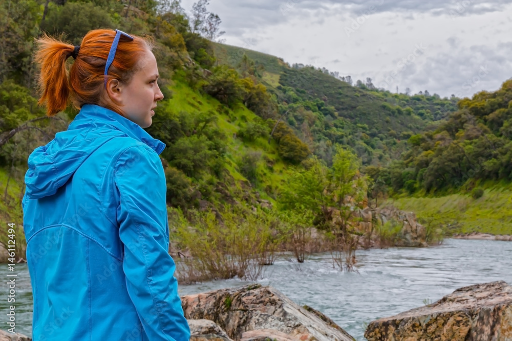 Naklejka premium Girl Standing on Rocks Near Fast River