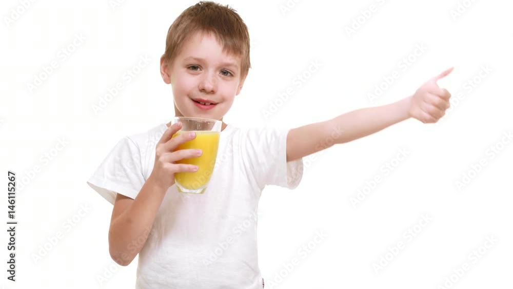 Elementary-school aged Caucasian boy gladly drinking orange juice from glass and showing ok at camera. White background Elementary-school aged Caucasian boy gladly drinking orange juice from glass and showing ok at camera. White background