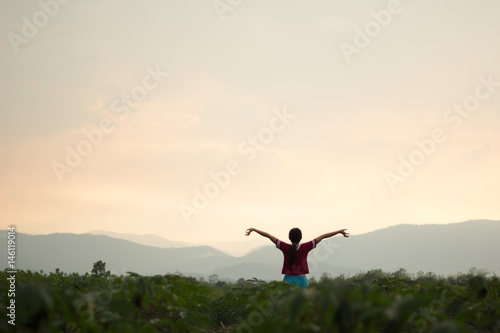 The girl stands in the middle of the mountain while the sun is falling