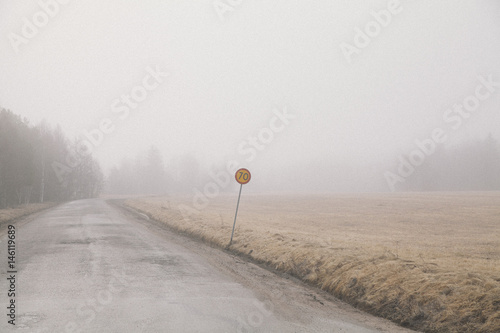 Country road by field in foggy weather against sky photo