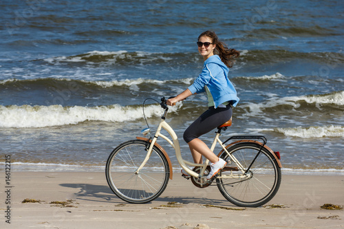 Teenage girl biking on beach