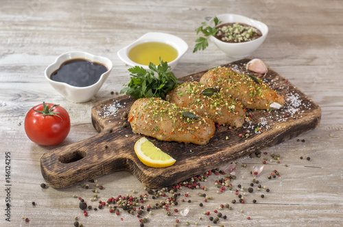 Photos Chicken fillet in marinade on a wooden board.
