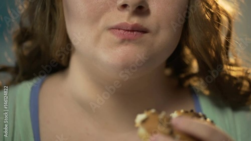 Plump woman biting donut and chewing it, overeating sweet pastry, face closeup