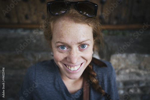 Close up view of attractive happy Caucasian woman with ginger hair looking and smiling at the camera.