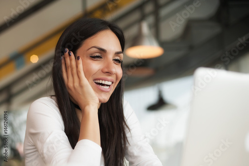 Woman chatting with friends using laptop with wireless internet connection