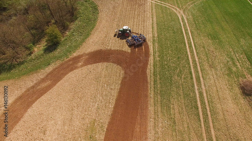  aerial view of a tractor at work on agricultural fields - tractor cultivating a field in spring