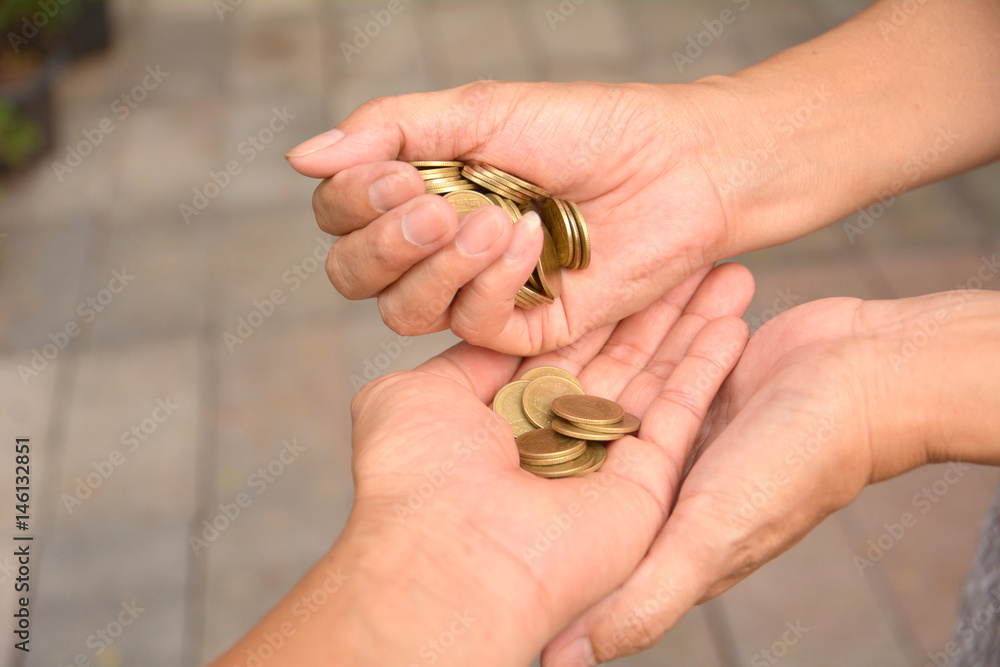 Female hand palm poured coin in the palm of male hands.Female hands pour down coins into hands of another person.