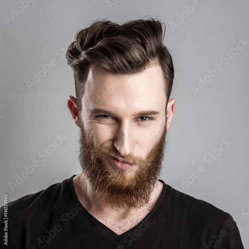 Treacherous and crafty young man isolated on gray background