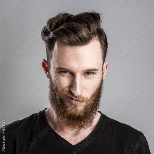 Quadro su tela Treacherous and crafty young man isolated on gray background