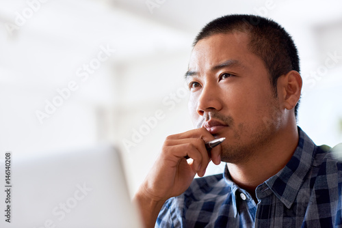 Photography Focused young Asian designer deep in thought at work