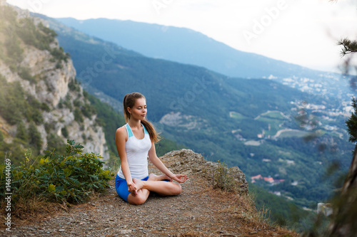 Young woman meditating outdoors, girl doing yoga high in the mountains, relaxation self-reflection concept