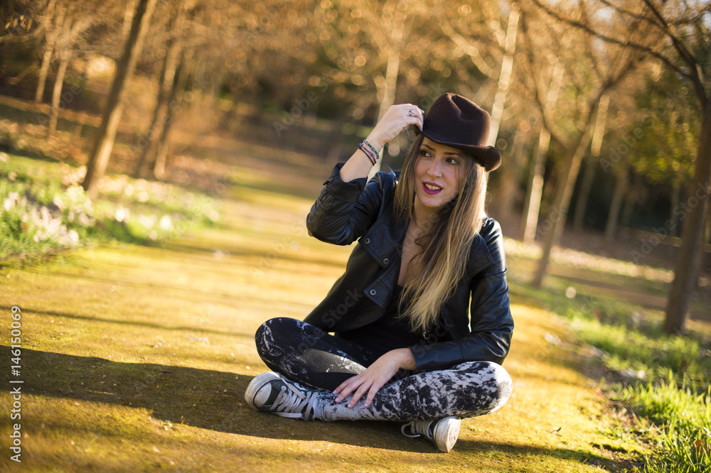 Portrait of a beautiful woman in hat on the park sitting on the floor. Portrait of a beautiful woman in hat on the park sitting on the floor.
