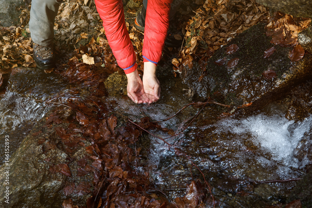 Thirsty hiker drinking water from a crystal clear spring Thirsty hiker drinking water from a crystal clear spring