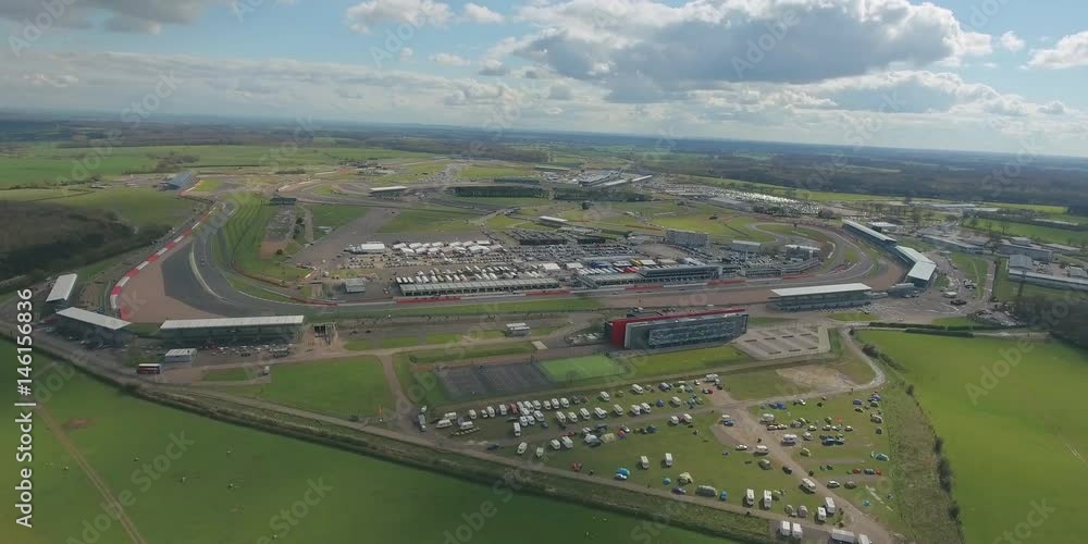 Aerial view of a big race on a sunny summer day in England. Cars going along the race. Full campsite. Aerial view of a big race on a sunny summer day in England. Cars going along the race. Full campsite.