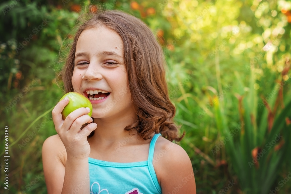 Child girl with an Apple on the background of the summer garden Child girl with an Apple on the background of the summer garden