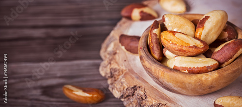 Foto Bowl of peeled brazil nuts on wooden background with copy space
