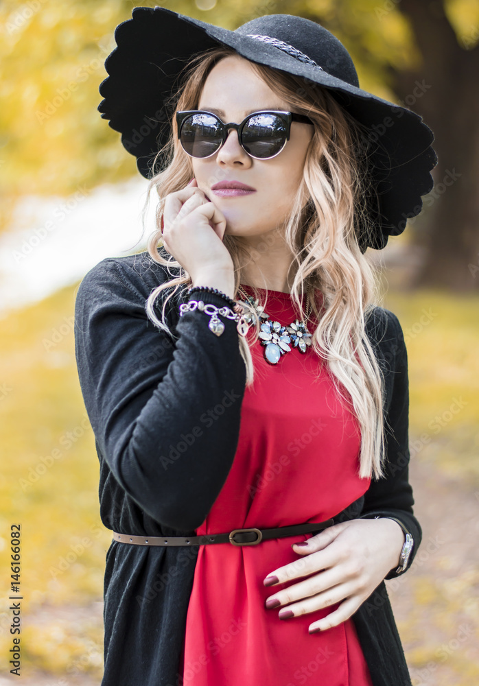 Young beautiful women dressed in fashionable clothes enjoying sunny spring day while wearing hat and sunglasses as accessories Young beautiful women dressed in fashionable clothes enjoying sunny spring day while wearing hat and sunglasses as accessories