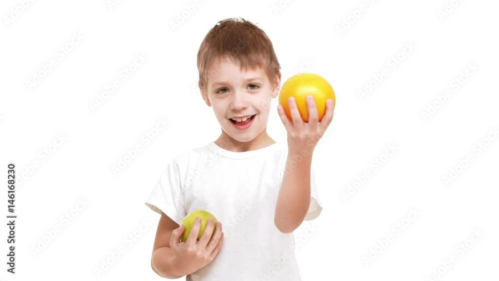 Elementary-school aged boy drawing orange to camera while holding in other hand apple. Footage on white background in slowmotion Elementary-school aged boy drawing orange to camera while holding in other hand apple. Footage on white background in slowmotion