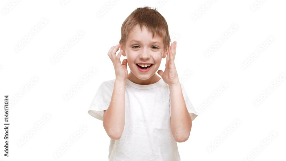 Young Caucasian boy standing on white background with face covered with hands. Then opening and trying to scare in slowmotion Young Caucasian boy standing on white background with face covered with hands. Then opening and trying to scare in slowmotion
