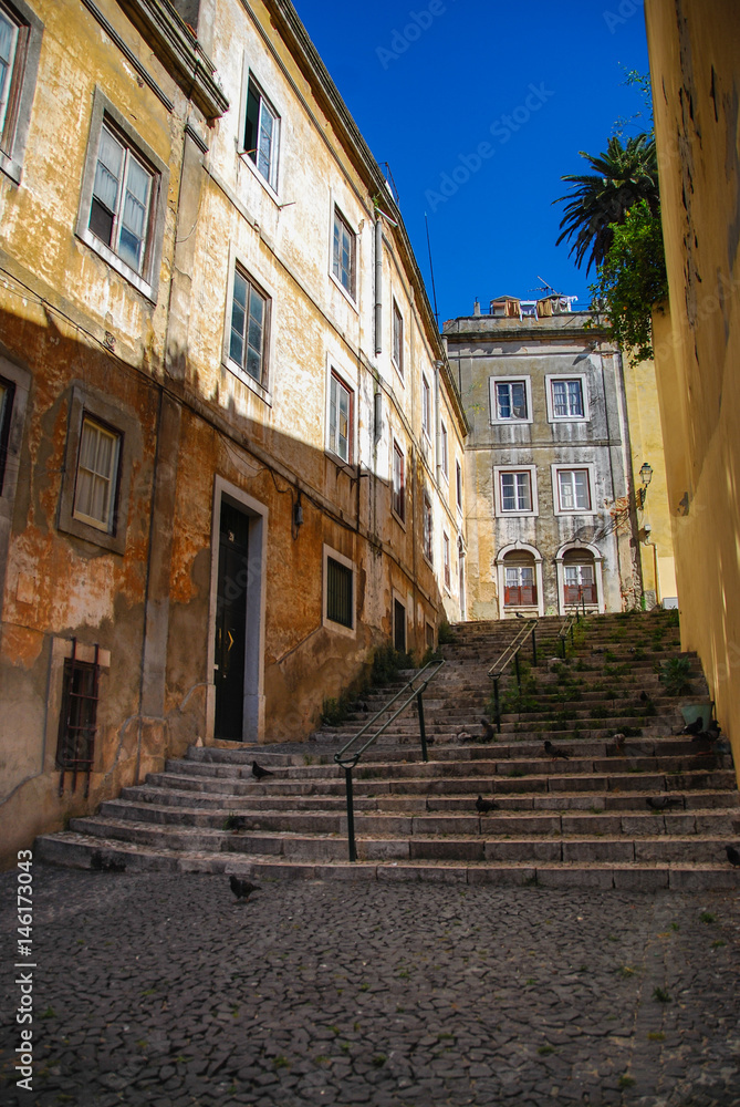 Steep stairs of Lisbon between historic building with rustic yellow facades