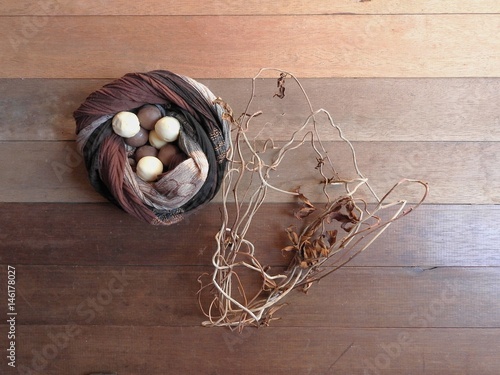 Nest of brown fabric with chocolates of white and black chocolate inside, thin branches of vine intertwined as a garnish on the wooden base photo