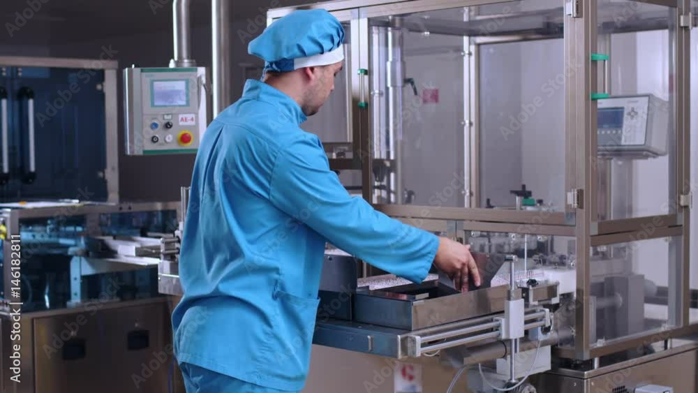 Factory operator control pharmaceutical packaging machine. Pharmaceutical manufacturing process. Pharmaceutical worker take packaging from manufacturing line. Pharmaceutical factory. Pharmacy factory Factory operator control pharmaceutical packaging machine. Pharmaceutical manufacturing process. Pharmaceutical worker take packaging from manufacturing line. Pharmaceutical factory. Pharmacy factory