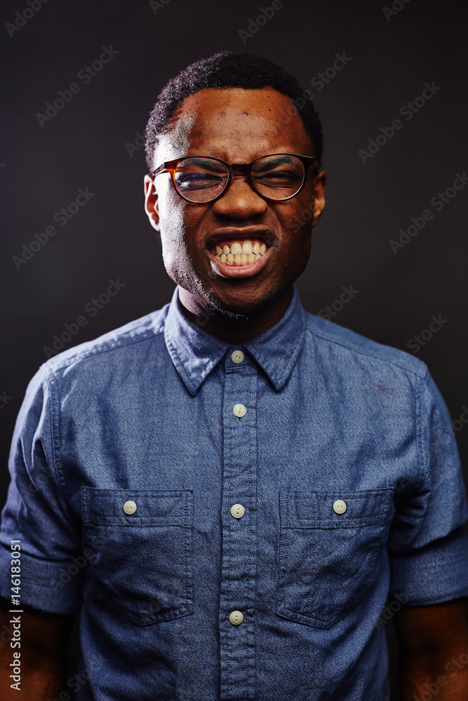 Obraz premium attractive young black male studio dark light gritting teeth silly